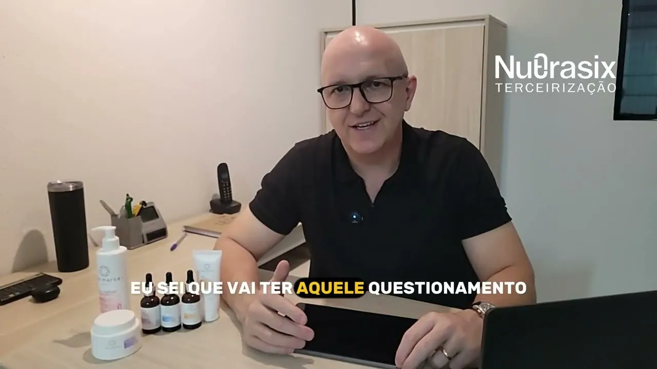 Representante da Nutrasix sentado à mesa com frascos e potes de cosméticos, apresentando o vídeo “Sua marca com a Nutrasix”